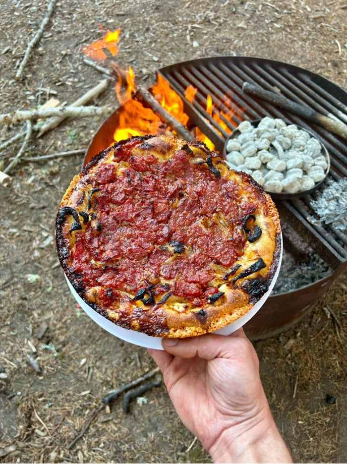 Cooked pizza by a campfire and coals